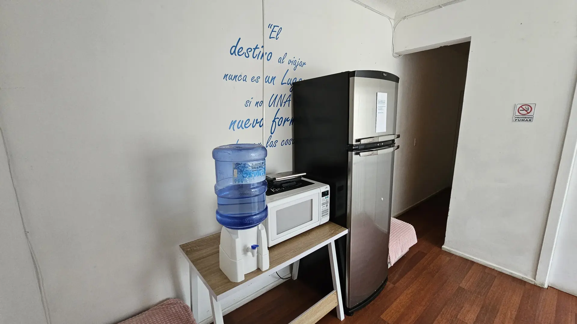 Segundo piso con un microondas, un refrigerador y un bidón de agua con dispensador