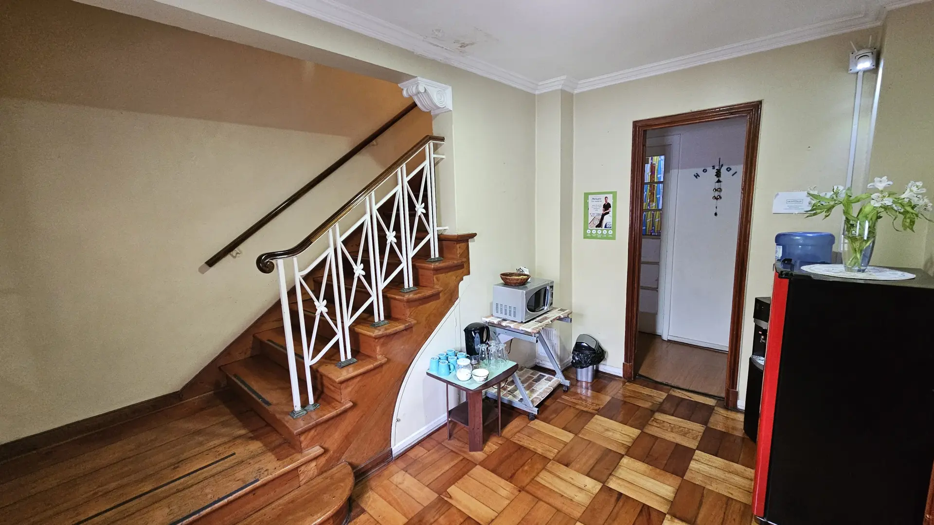 Entrada con escalera, pequeño refrigerador, tazas, vasos y un microondas