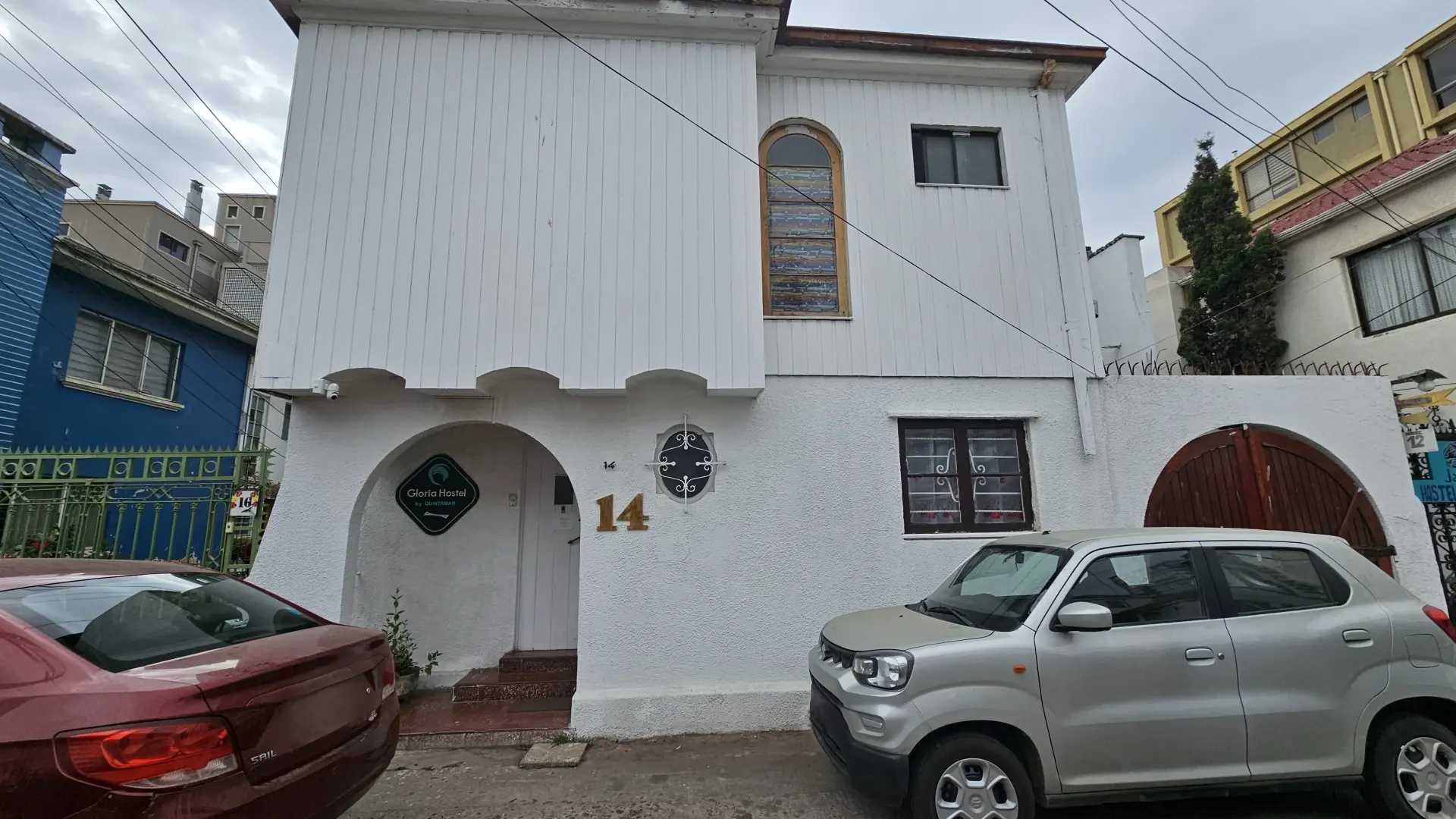 Exterior de Gloria Hostel con dos vehiculos y el número de la casa