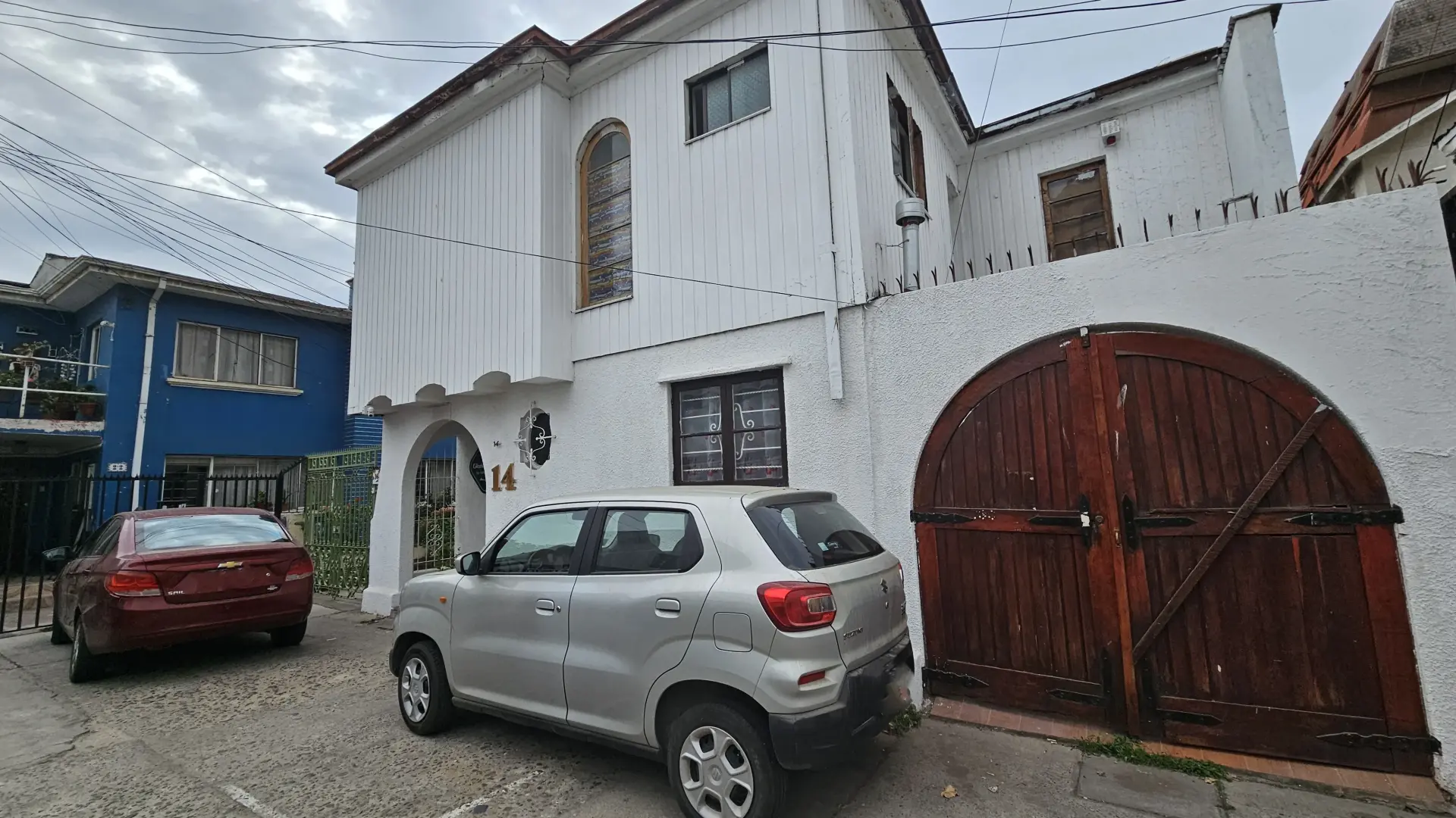 Exterior con dos vehículos y una entrada de madera